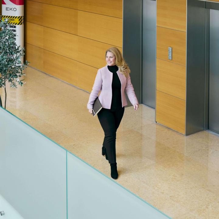 γυναίκα χαμογελαστή περπατάει σε είσοδο κτιρίου